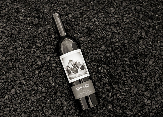 Elegant wine bottle with black and white label featuring vintage camera image on dark textured background.