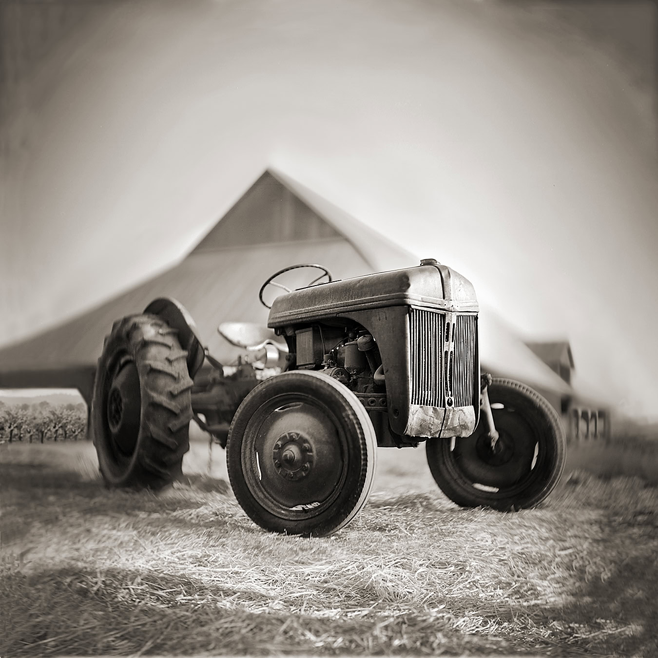 Black and white vintage tractor on a farm with a barn in the background.